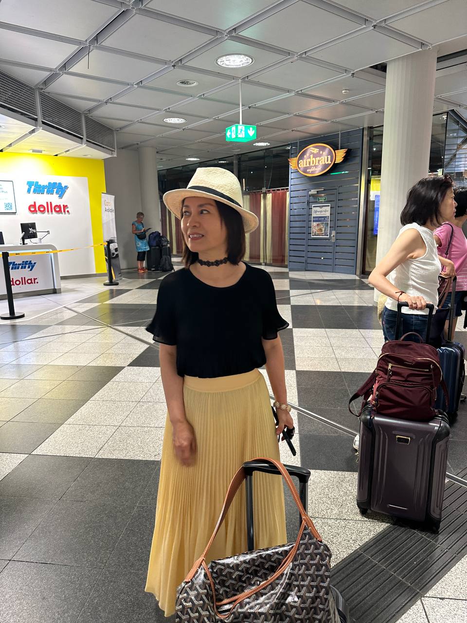 A traveler waiting with luggage in the airport rental car area.