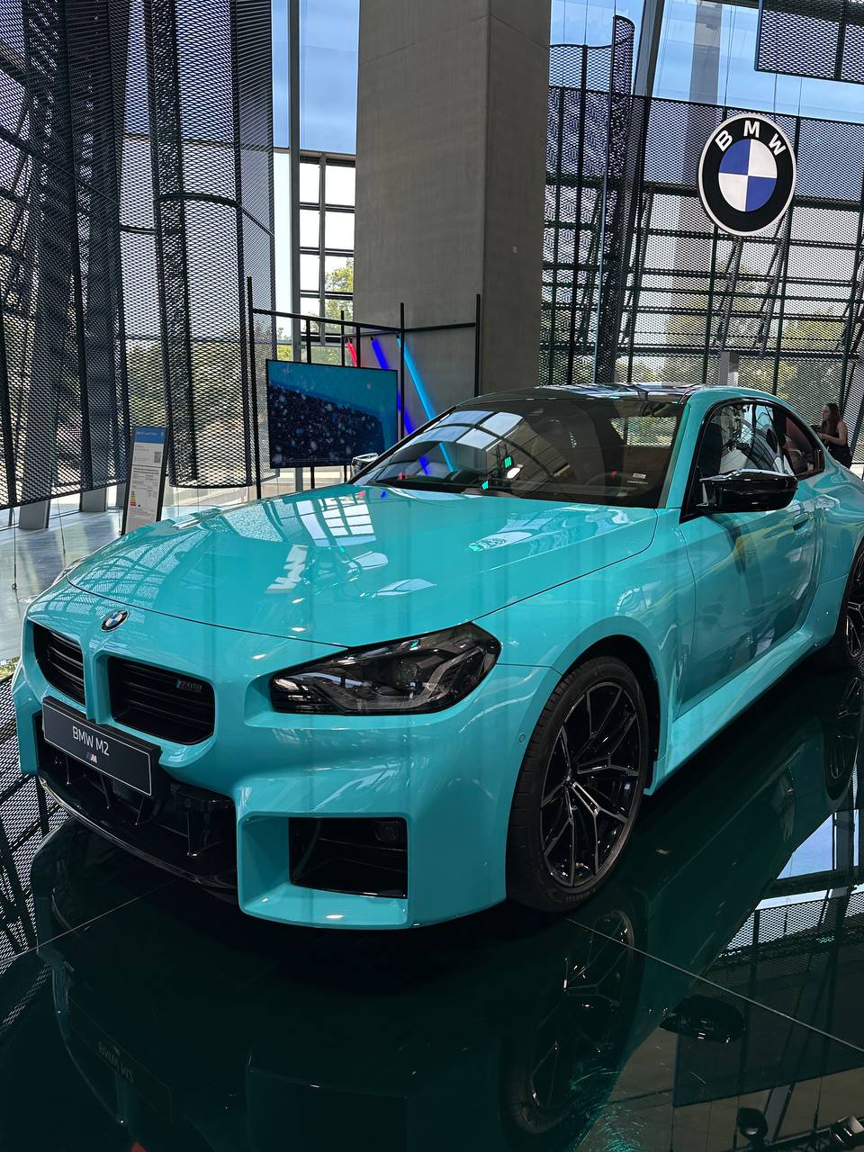 A bright turquoise BMW M2 on display inside BMW Welt.