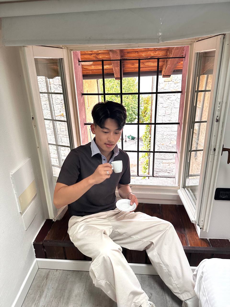 Steven 坐在窗台上喝咖啡。
