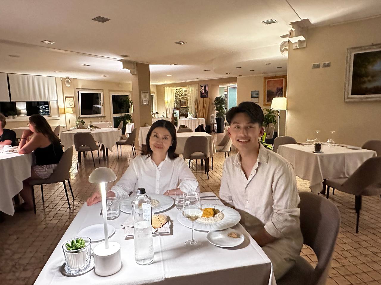 当晚在当地米其林餐厅：母子同桌，白色桌布与暖黄的灯。